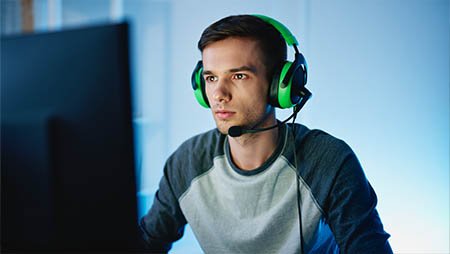 Парень сидит в наушниках и играет в компьютер